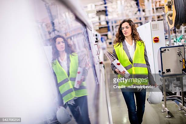 giovane lavoratrice che cammina attraverso la fabbrica - worker inspecting steel foto e immagini stock