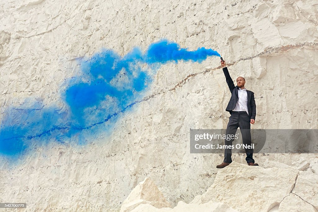 Man in suit with blue flare on chalk cliff