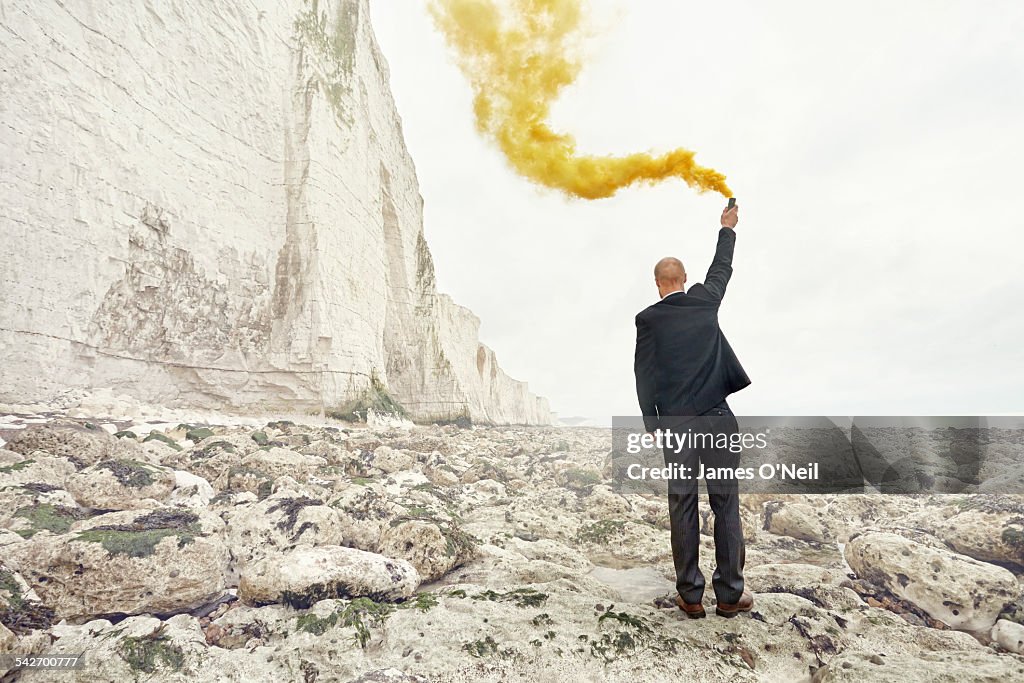 Man in suit with yellow flare on chalk cliff