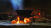 Pot of food on burning wood fire.