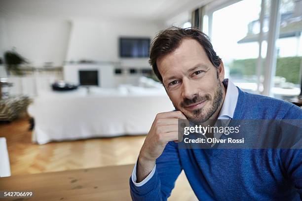 portrait of smiling man at home - mano sul mento foto e immagini stock