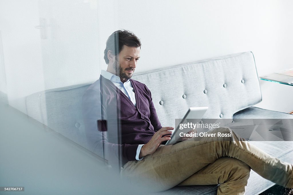 Man sitting on couch holding digital tablet