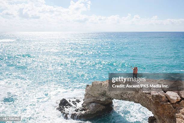 couple take selfie pic on natural bridge, sea surf - middlebare afstand stockfoto's en -beelden