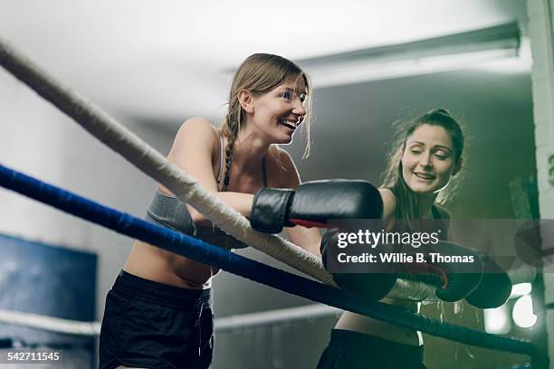 two female fighters leaning on ropes - boxing ropes stockfoto's en -beelden