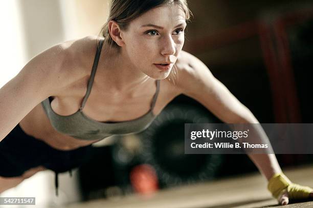 focused female boxer doing push-ups - liegestütze stock-fotos und bilder