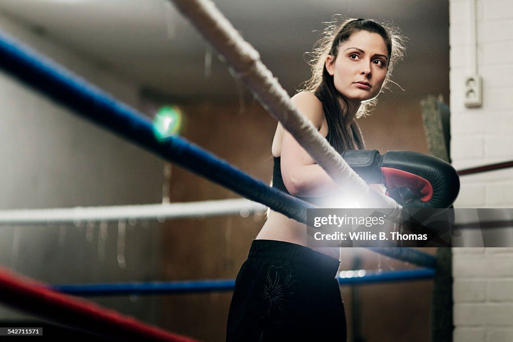 Determined female fighter leaning on ropes