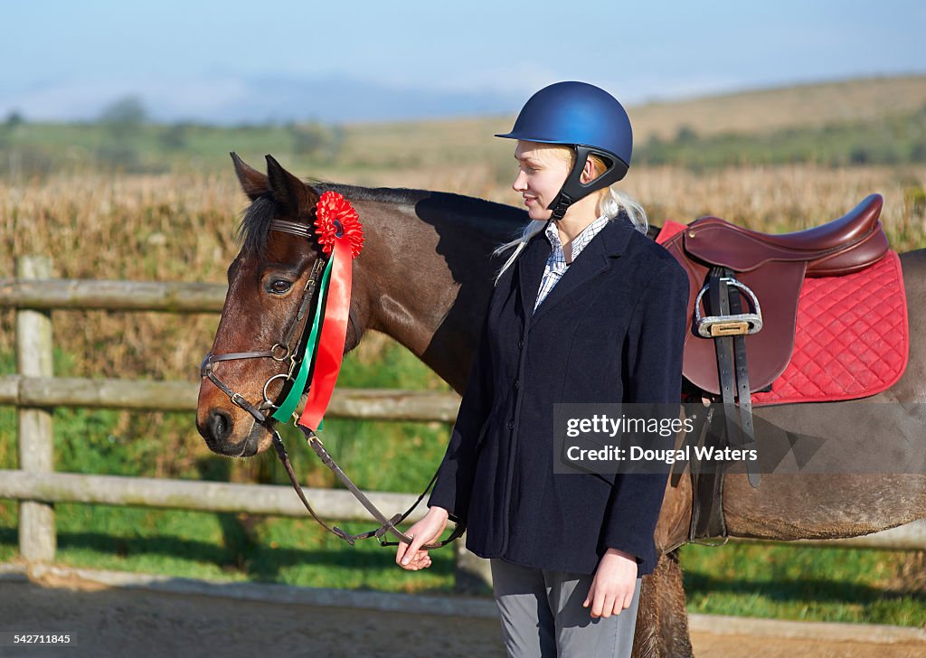 Female jockey standing with prize winning horse.