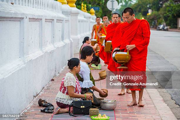 monks collecting alms in luang prabang. - alms stock pictures, royalty-free photos & images