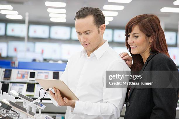 woman and man looking at a tablet - elektromarkt foto e immagini stock