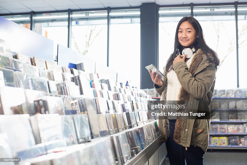 A girl is looking for CD's and DVD's in a store