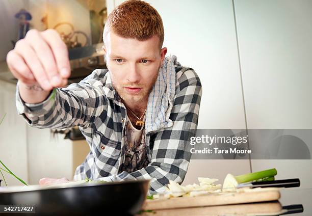 young man cooking at home - seasoning - fotografias e filmes do acervo
