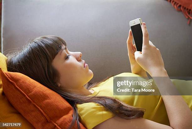 young woman with mobile lying on sofa - couch stock pictures, royalty-free photos & images