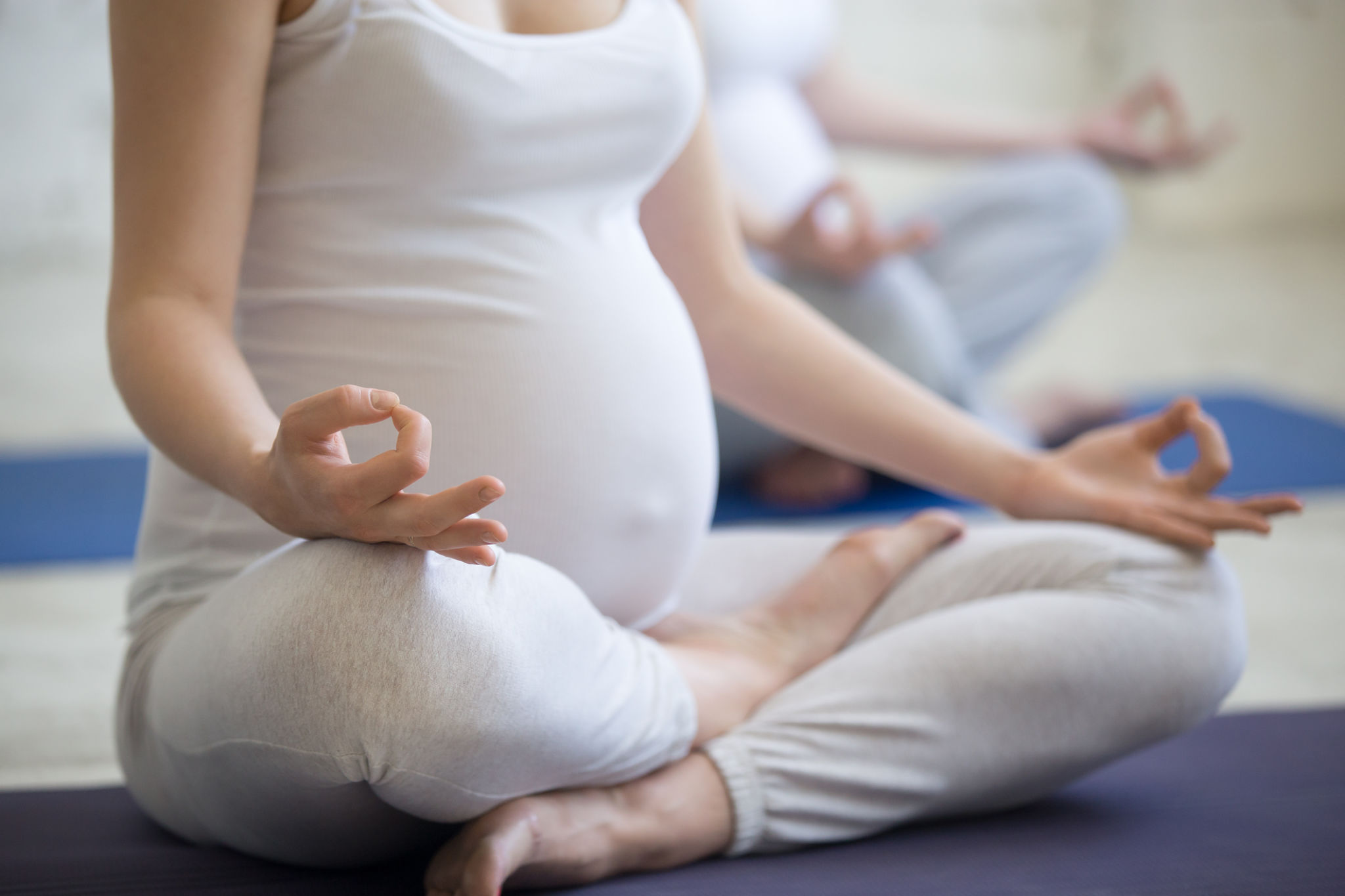 Pregnant young women doing prenatal yoga. Close-up of torso Pregnant young women doing prenatal yoga. Close-up of torso