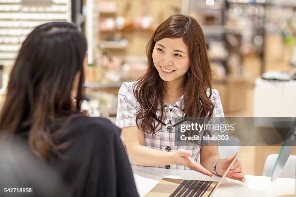 sales clerk using a laptop computer to assist customer - klantgericht stockfoto's en -beelden