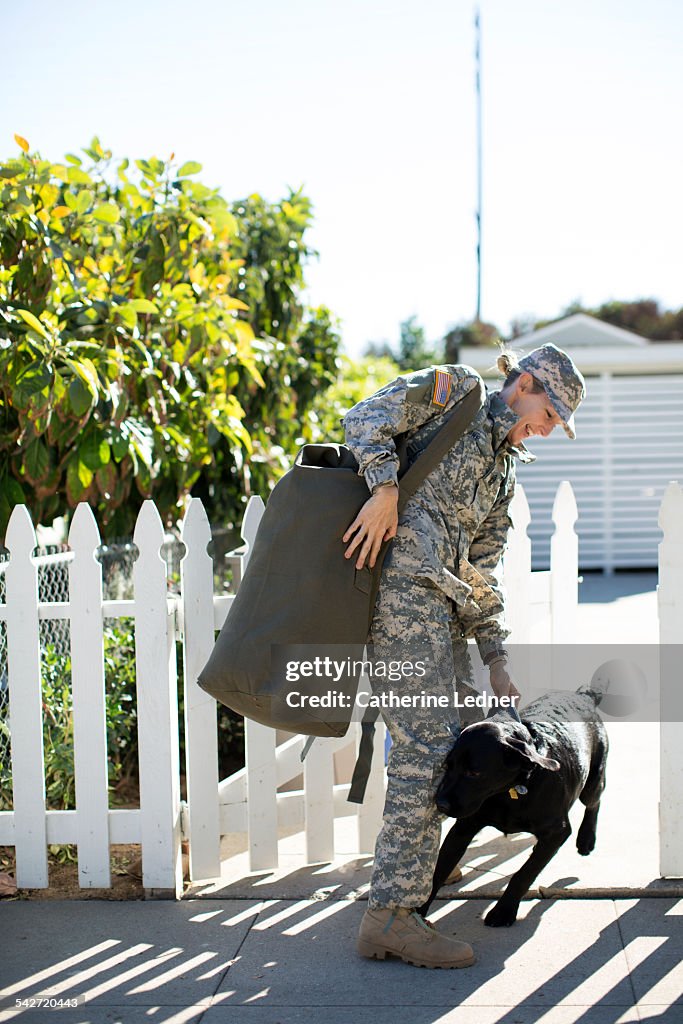Military Woman Greeting her dog at picket fence