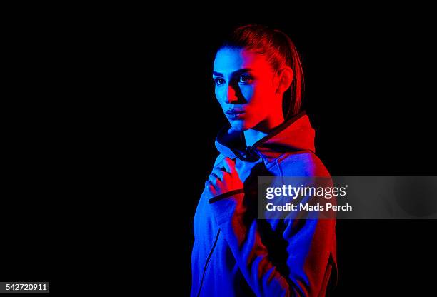 young woman photographed with creative lighting - red jacket stock pictures, royalty-free photos & images