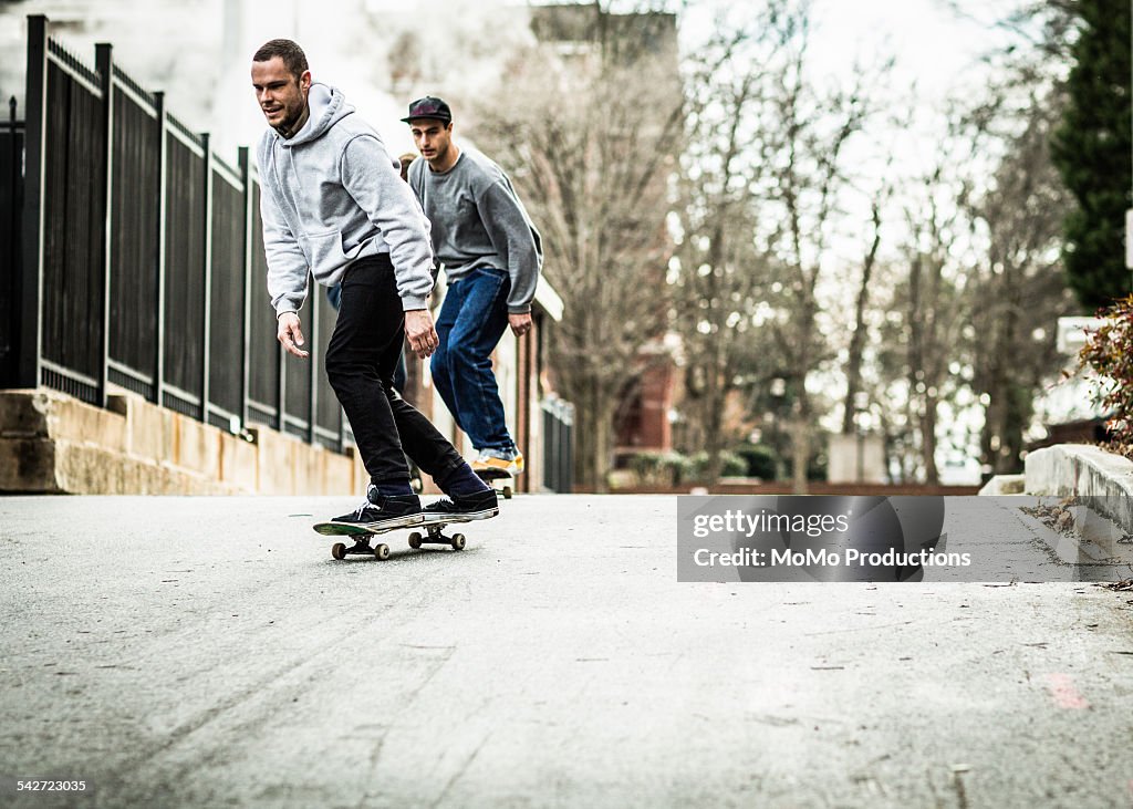 Two men skateboarding in urban environment.
