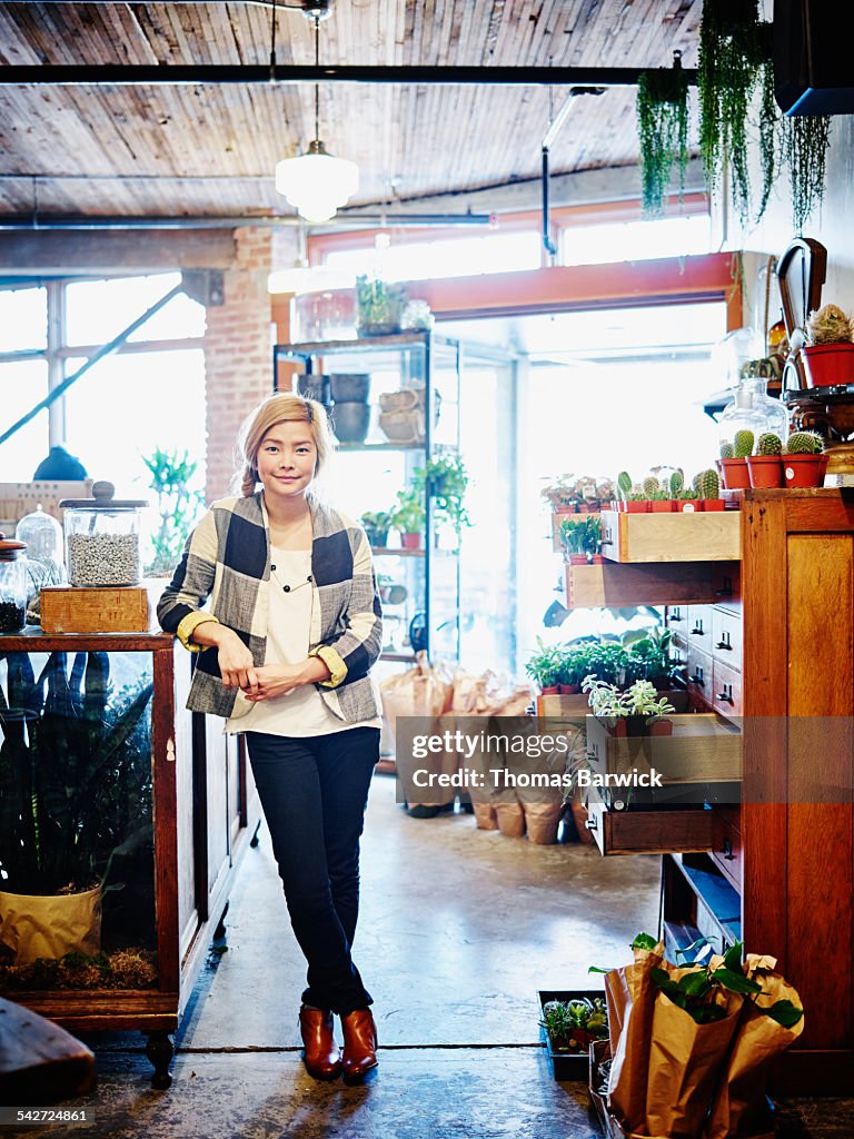 Smiling female shop owner standing in plant store