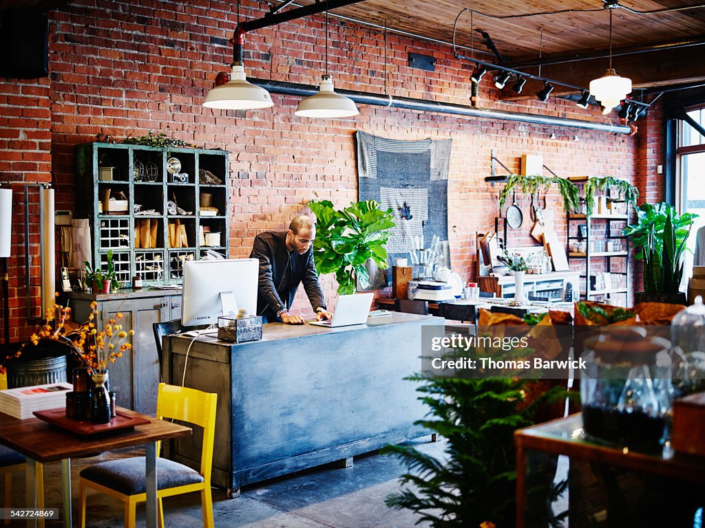 Shop owner at counter working on laptop