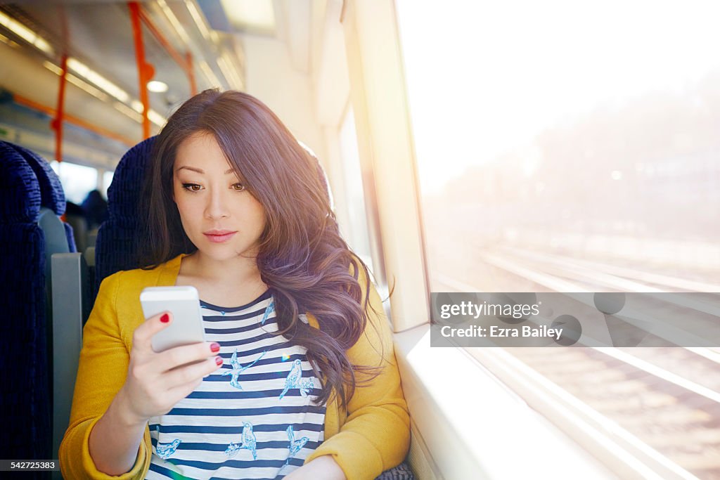 Woman on a train looking at her phone.