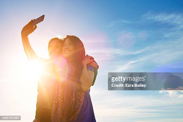 girl friends taking a selfie and smiling. - photographing sunset stock pictures, royalty-free photos & images