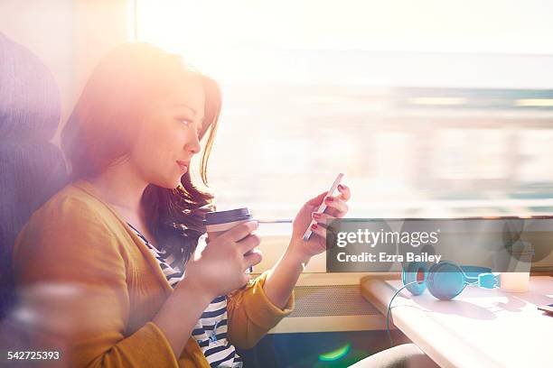 woman on a commuter train looking at her phone. - voertuiginterieur stockfoto's en -beelden