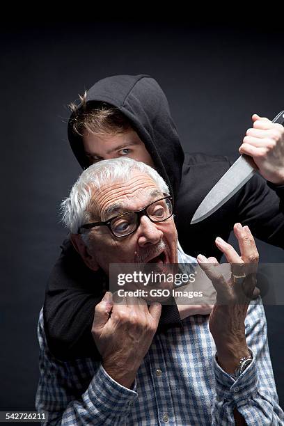 hoodie teen threatens senior with knife - mugger stock pictures, royalty-free photos & images
