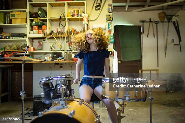 teenage girl drumming in garage. - playing drums fotografías e imágenes de stock