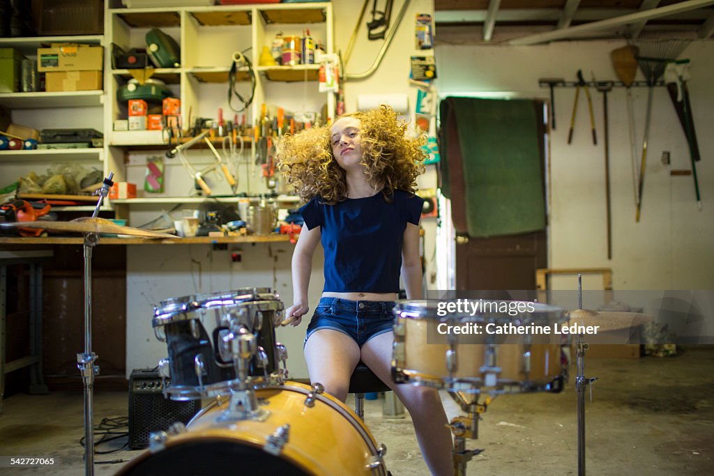 Teenage girl drumming in garage.