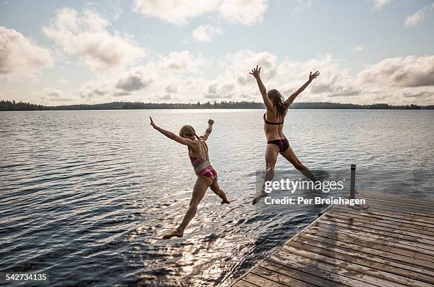 mother and a daughter jumping off a dock - ely minnesota stock pictures, royalty-free photos & images