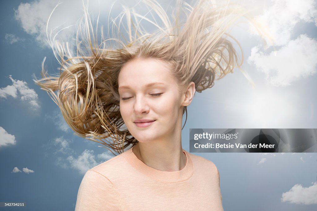 Young woman shaking her hair in wind