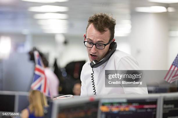 Financial trader speaks on telephone following news of the European Union referendum vote at ETX Capital in London, U.K., on Friday, June 24, 2016....