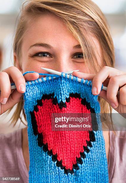 young woman holding knitted red heart scarf - knitting stock pictures, royalty-free photos & images