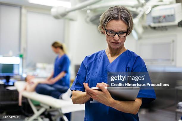 doctor with digital tablet in operating theatre - electronic medical record stock pictures, royalty-free photos & images