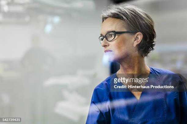 portrait of mature female doctor - person looking through window stock pictures, royalty-free photos & images