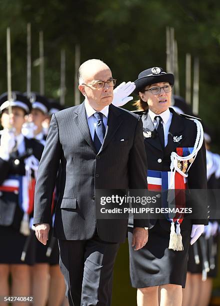 French interior minister, Bernard Cazeneuve reviews the newly promoted police chiefs with school director Helene Martini during a ceremony of the...