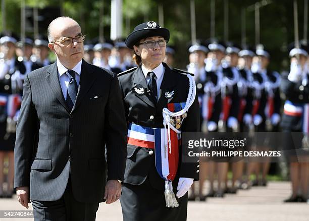 French interior minister, Bernard Cazeneuve reviews the newly promoted police chiefs with school director Helene Martini during a ceremony of the...