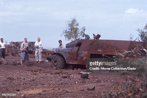 Western male and female tourists posing among the destroyed military vehicles and armament from the Six Day War, located outside of the town of...