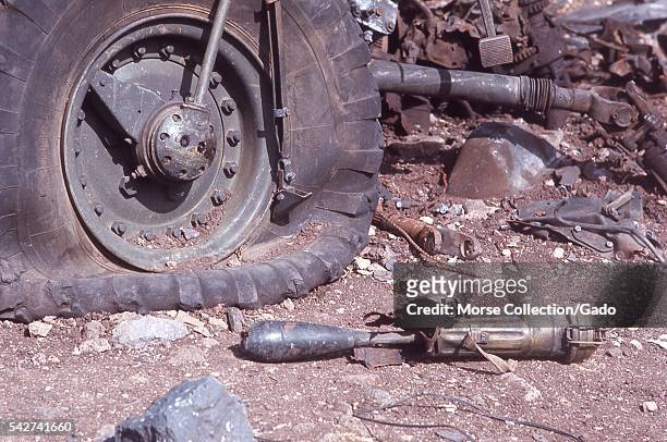 Close up view of a deflated military truck tire, chunks of metal, and the remnants of a shoulder-fired missile rocket among the rubble left over from...