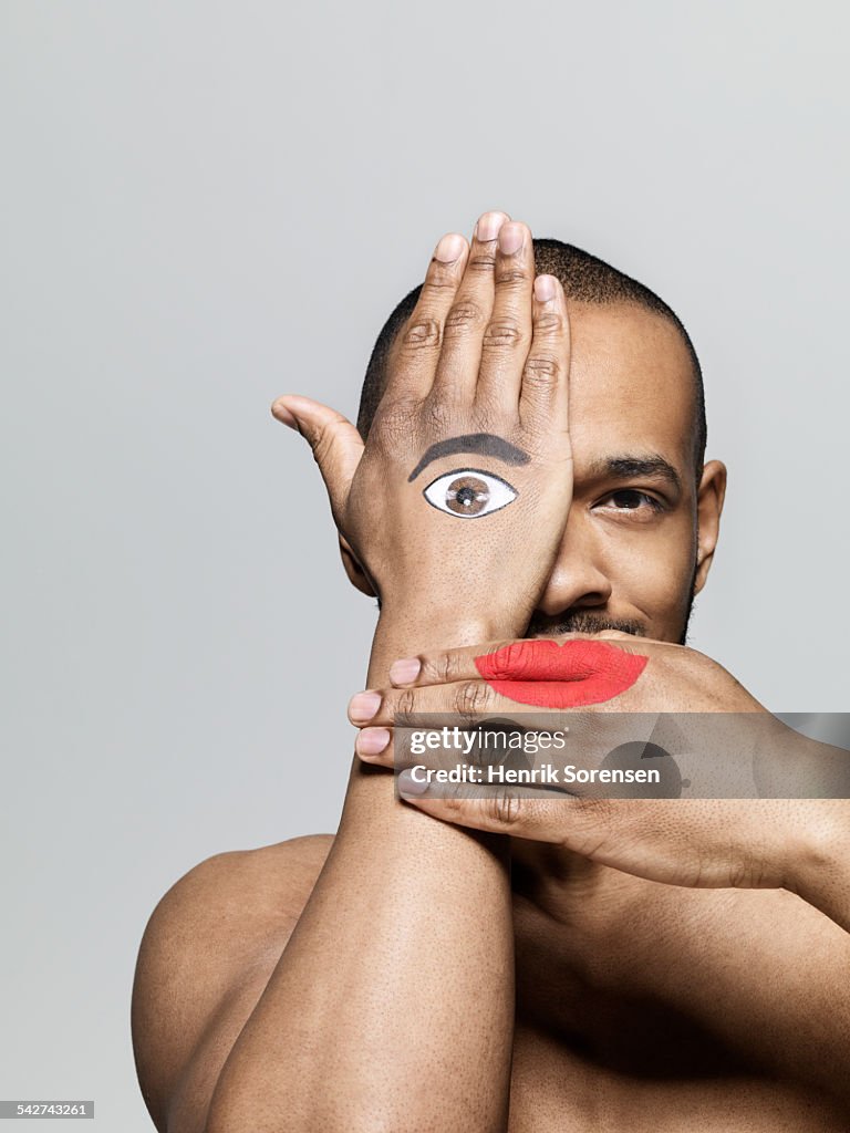Man with lips and eye painted on his hands