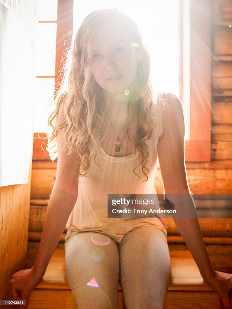 Young woman in flared light from log cabin window