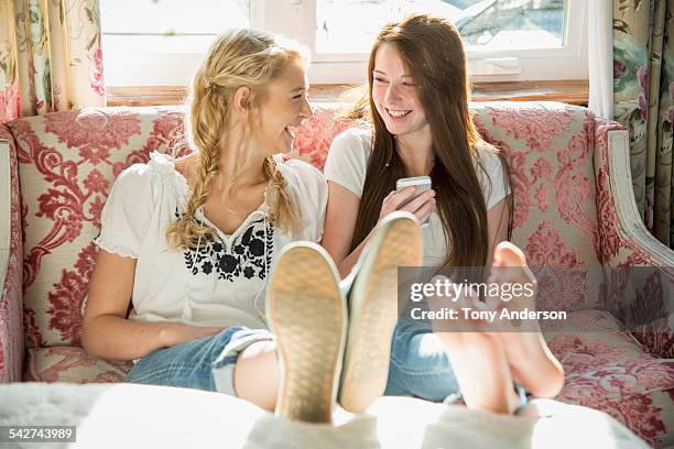 laughing teen girls at home with phone - girl barefoot stock-fotos und bilder