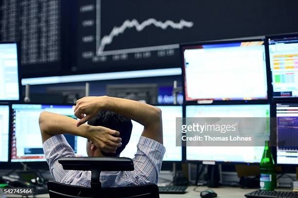 Trader sits at his desk under the day's performance board that shows a dive in the value of the DAX index of companies at the Frankfurt Stock...