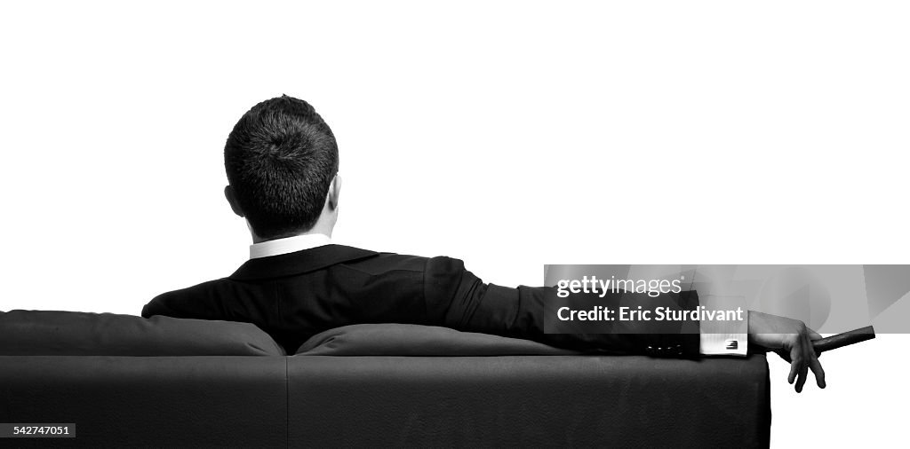 Man in suit sitting on couch with cigar