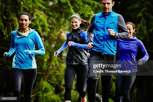 smiling group of friends running together - group of people running stock pictures, royalty-free photos & images