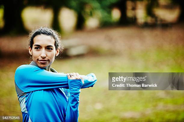 female runner stretching before morning run - joggerin park stock-fotos und bilder
