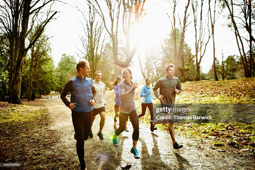 Smiling friends running together in park