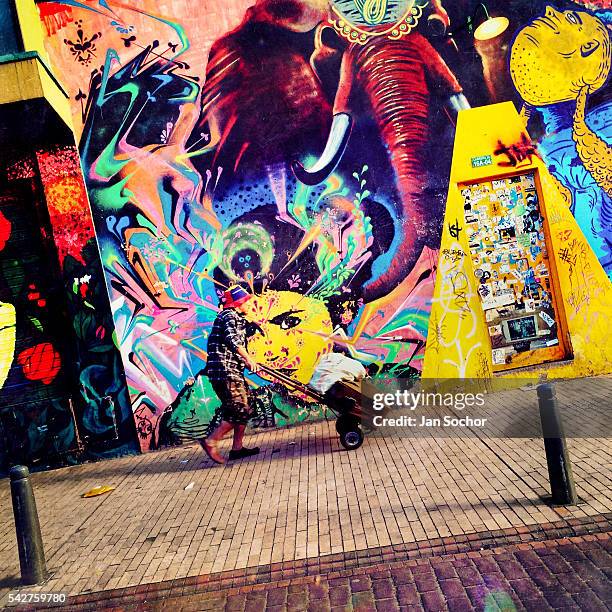 Colombian street vendor passes in front of a graffiti artwork, created by an artist named Stinkfish, in La Candelaria, Bogotá, Colombia, 14 February,...