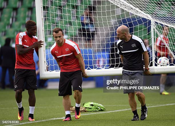 Switzerland's defender Francois Moubandje , Switzerland's midfielder Xherdan Shaqiri and a team manager carry a goal during a training session at the...