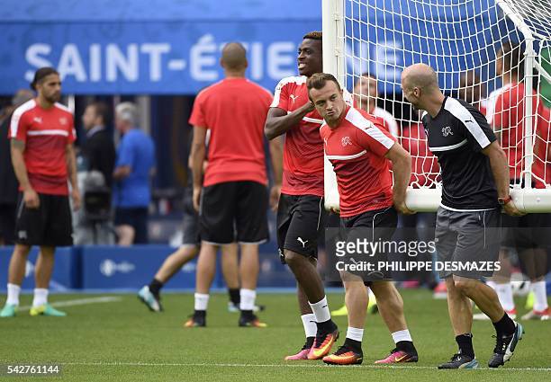 Switzerland's defender Francois Moubandje , Switzerland's midfielder Xherdan Shaqiri and a team manager carry a goal during a training session at the...
